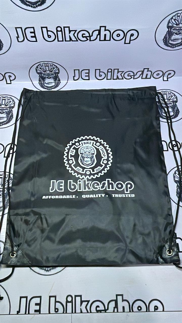 Black drawstring bag with 'JE Bikeshop' logo on a branded background