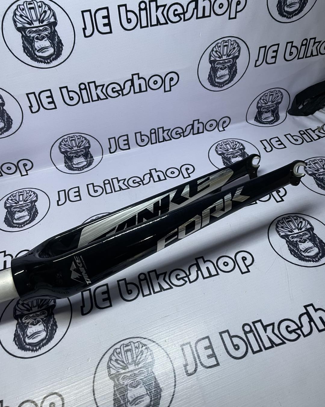 Bicycle fork on a white background with 'JE Bikeshop' branding.