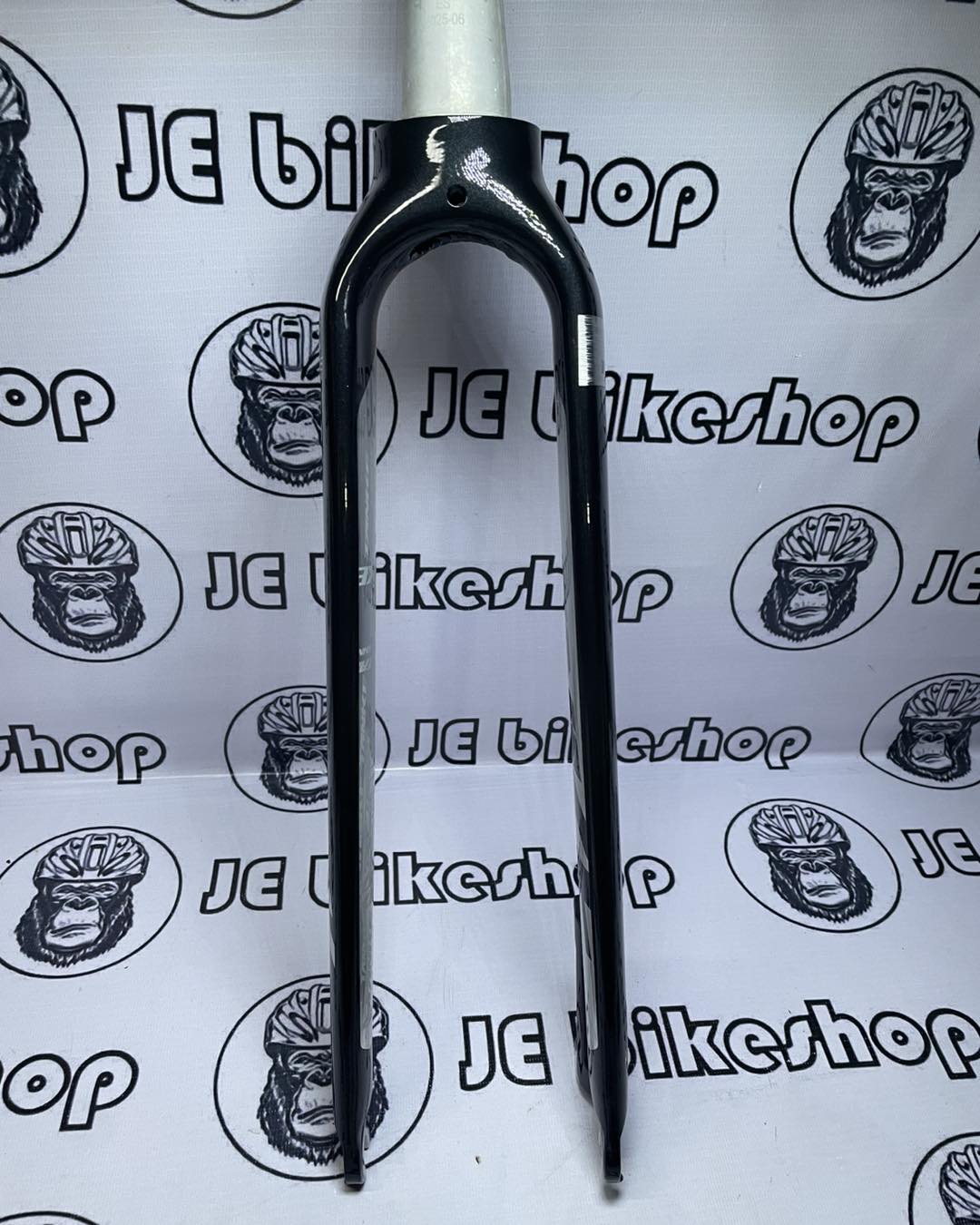 Bicycle fork on a white background with 'JE Bikeshop' branding.