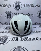 White bicycle helmet on a white background with 'JE Bikeshop' branding.