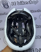 White bicycle helmet with black interior on a white background with 'JE bikeshop' branding.