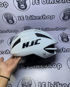 White HJC helmet held by a hand against a branded background